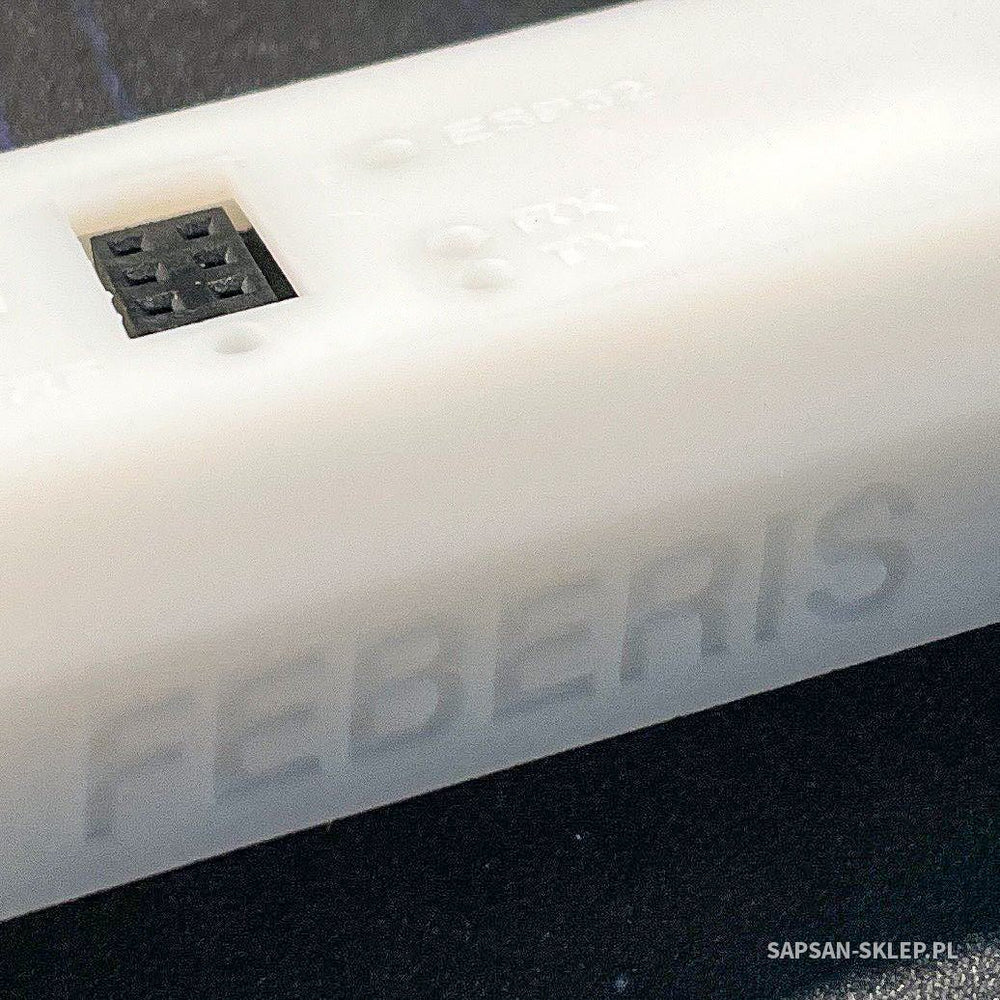 Close-up of the FEBERIS module in a white 3D-printed case - the embossed FEBERIS text on the side, a black JTAG socket visible through a cutout and pin labels (ESP32, RX, TX), SAPSAN-SKLEP.PL watermark