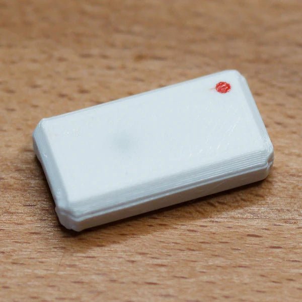 A single assembled white USB Nova case with a red LED, on a wooden surface