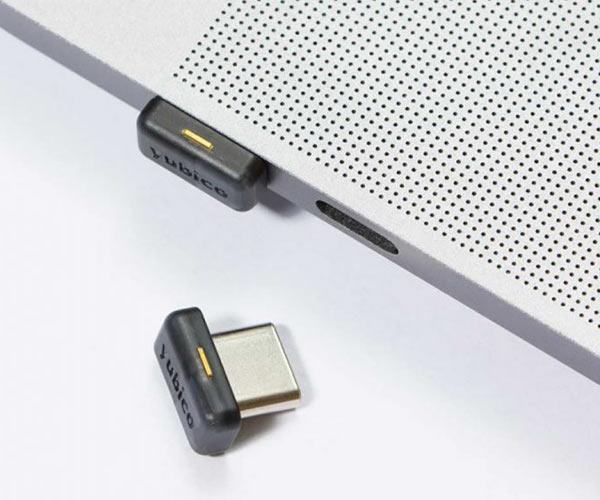 Mały czarny klucz YubiKey 5C Nano wpięty w port USB-C laptopa, ledwo wystaje, drugi egzemplarz obok