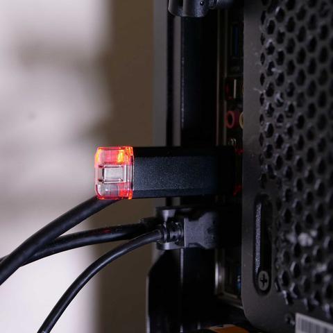 Czarny BadUSB MalDuino W podłączony do tylnego panelu komputera ze świecącą czerwoną diodą LED
