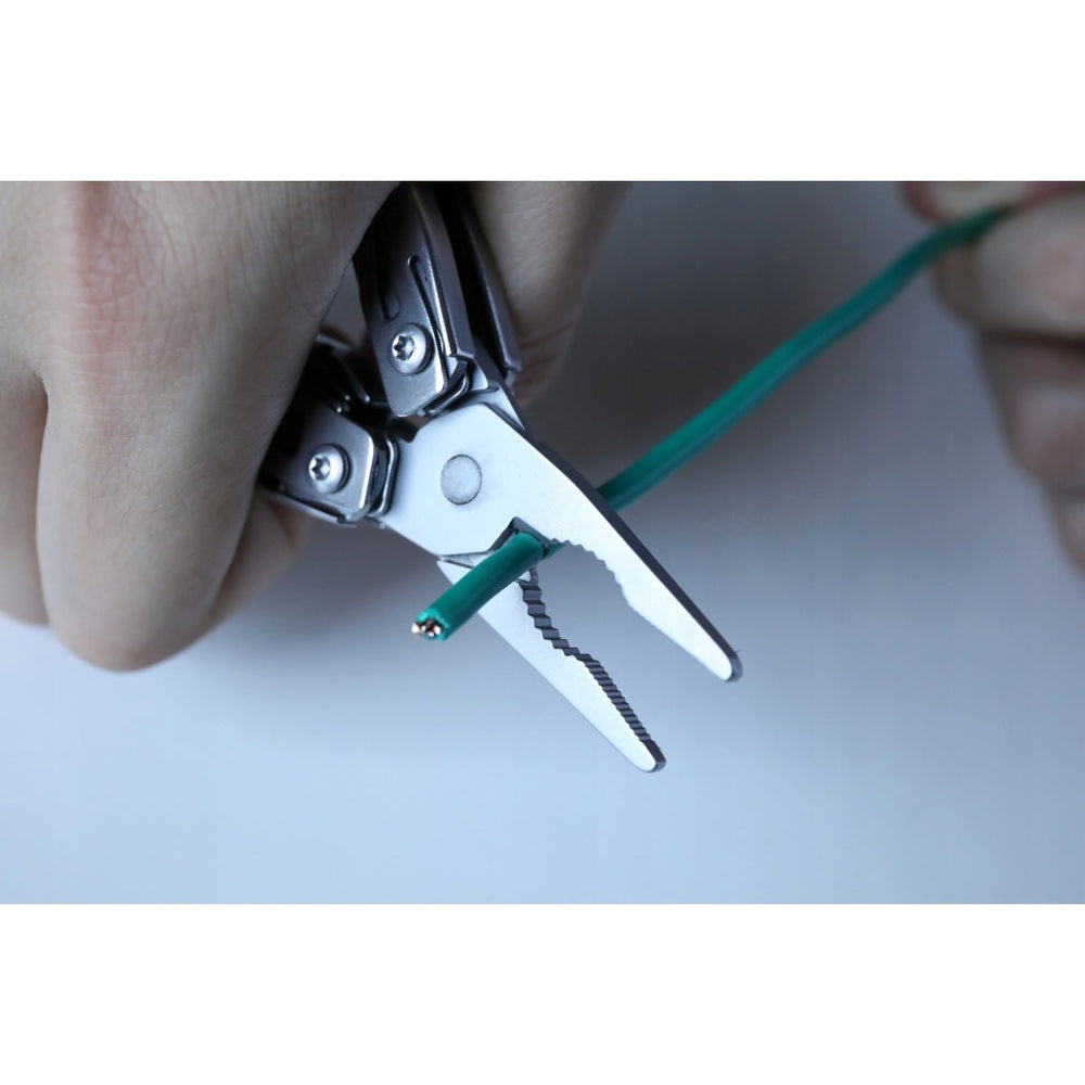 Dłoń ściąga izolację z zielonego przewodu szczypcami multitoola NexTool Mini Flagship