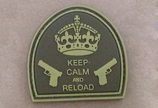 Naszywka - łukowata naszywka w odcieniach oliwki i piasku z koroną, dwoma pistoletami i napisem Keep Calm And Reload, na jasnobrązowym tle