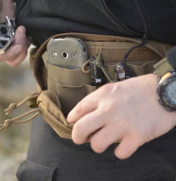Helikon-Tex Bandicoot waist pack in coyote worn on the hip, open - a phone, a flashlight, a multitool and other EDC gear inside, a hand opening it, outdoors