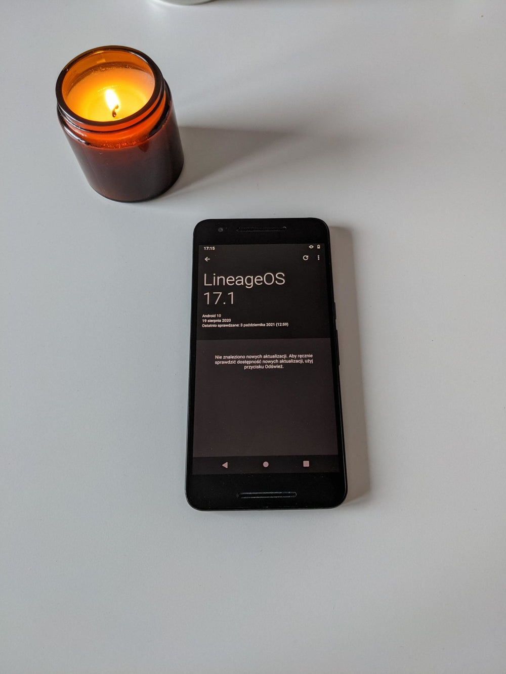 Czarny smartfon Nexus 6p z ekranem informacji o systemie LineageOS 17.1 na bazie Androida 10, obok świecy