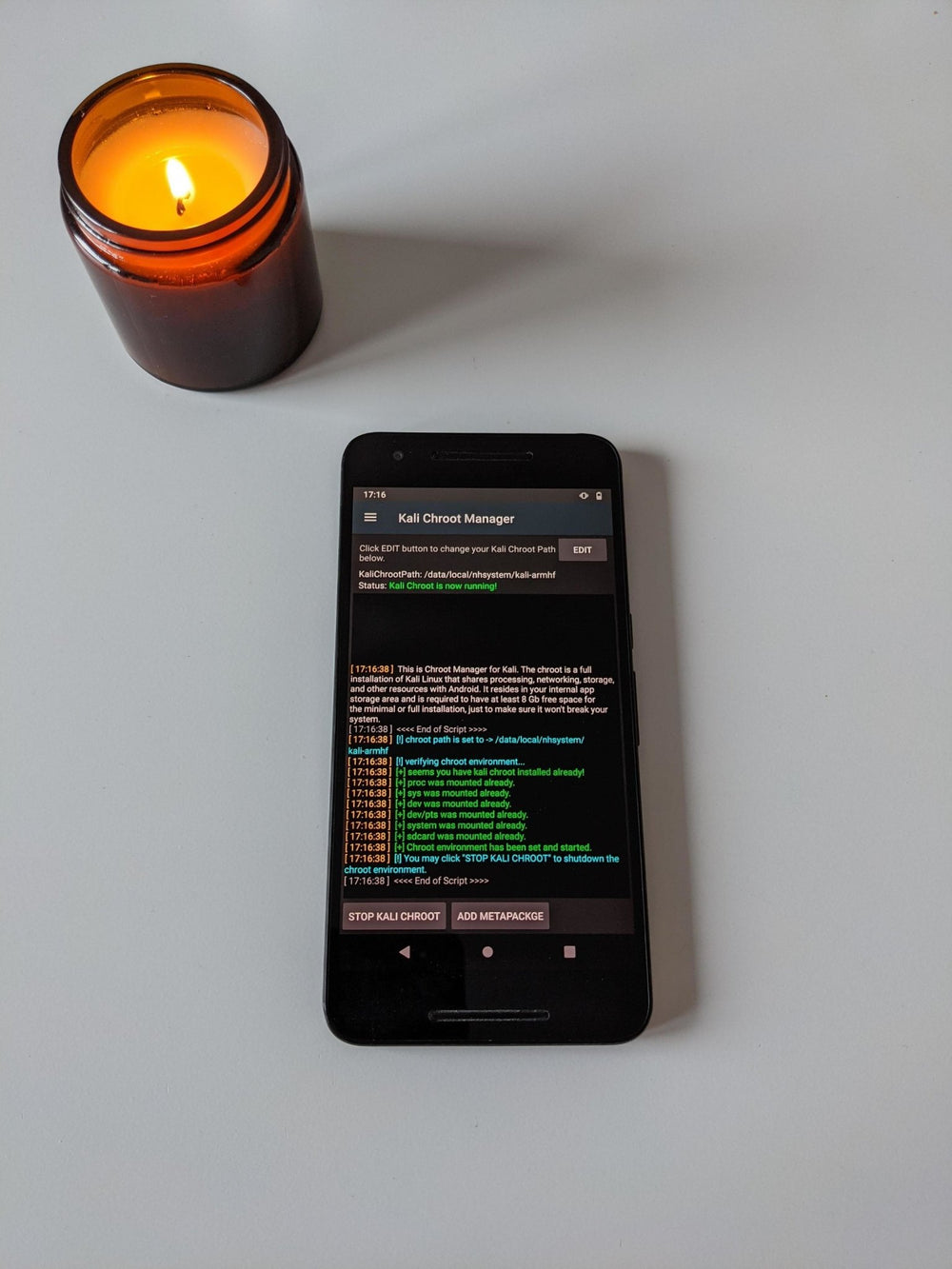 Czarny smartfon Nexus 6p z aplikacją Kali NetHunter na ekranie Kali Chroot Manager z logiem uruchomionego środowiska chroot, obok świecy