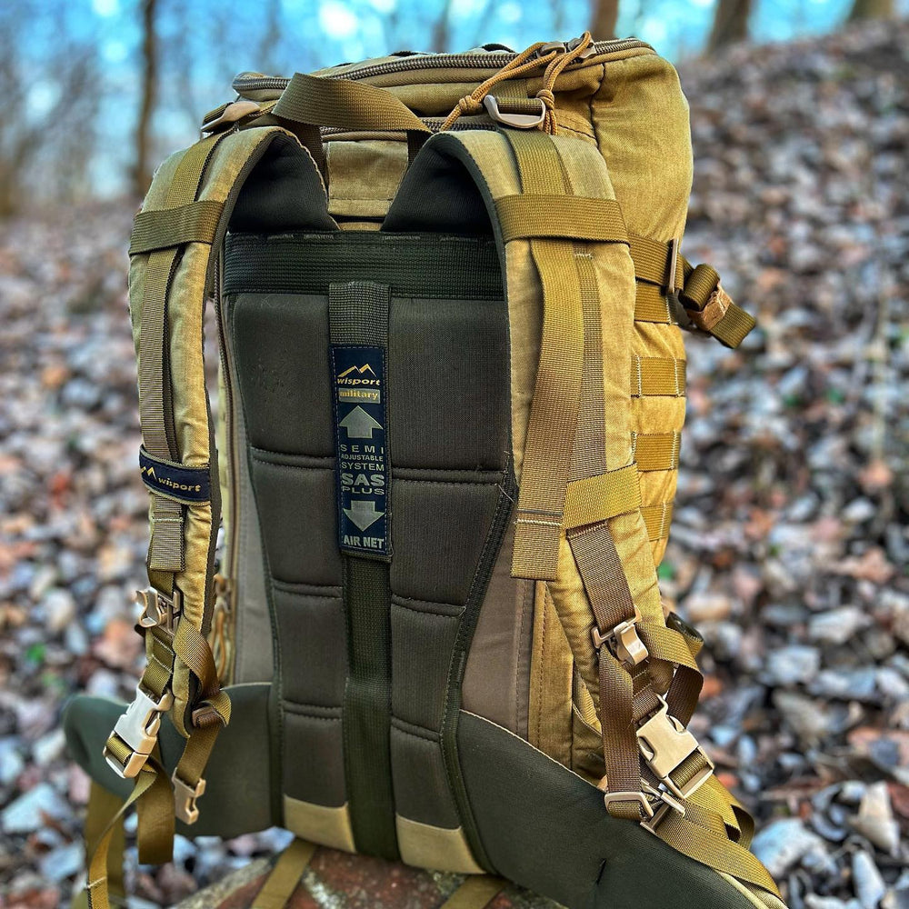Plecak Wisport ZipperFox pokazany od strony pleców (egzemplarz w kolorze piaskowym) - wyściełane szelki i wentylowany system nośny z etykietą SAS PLUS oraz logo wisport military, na tle jesiennego lasu