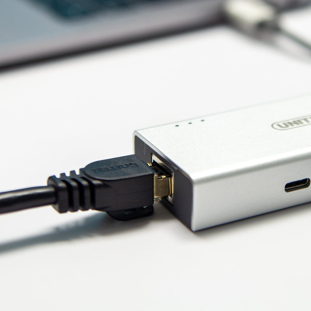 Black Unitek Cat.7 3 m cable with RJ45 plug connected to a silver network adapter, desk scene
