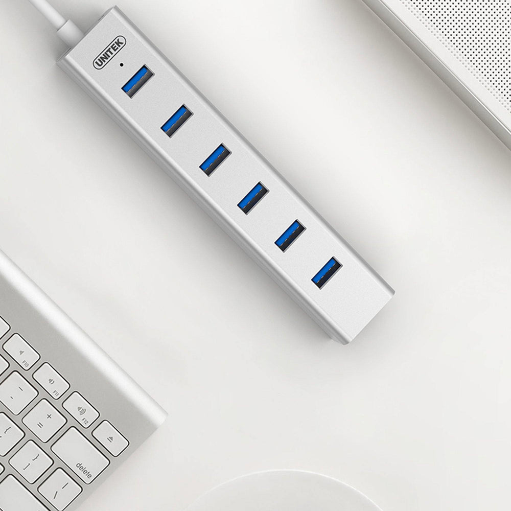Unitek Y-3090 USB hub on a white desk next to an Apple keyboard, top view of the USB 3.0 ports