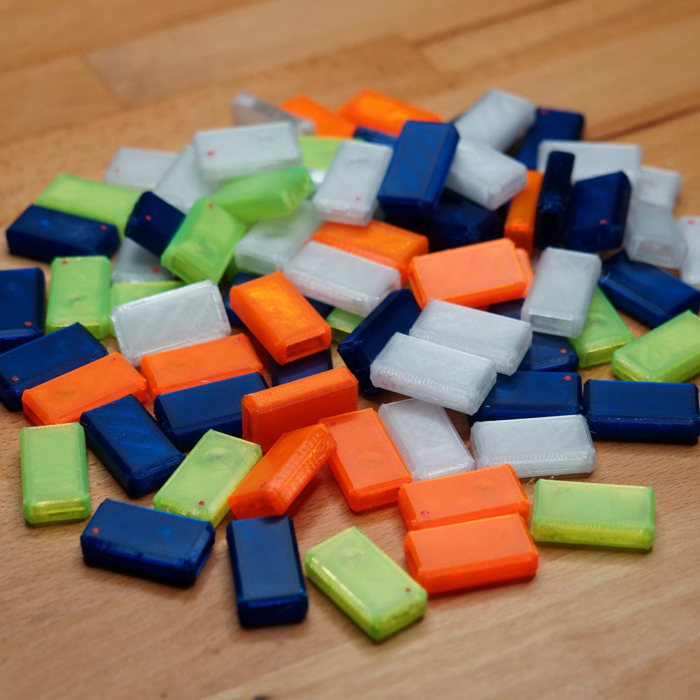 A large pile of replacement USB Nova cases in blue, green, orange and clear, on a wooden surface