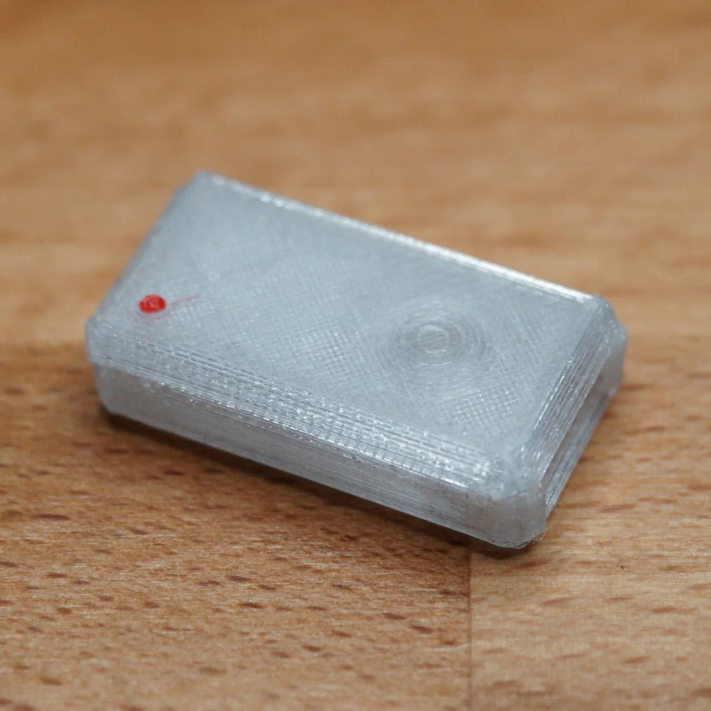 A single assembled clear USB Nova case with a red LED, on a wooden surface
