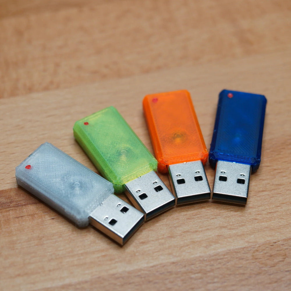 Four USB Nova devices in replacement cases (clear, green, orange and blue) with USB-A plugs, fanned out