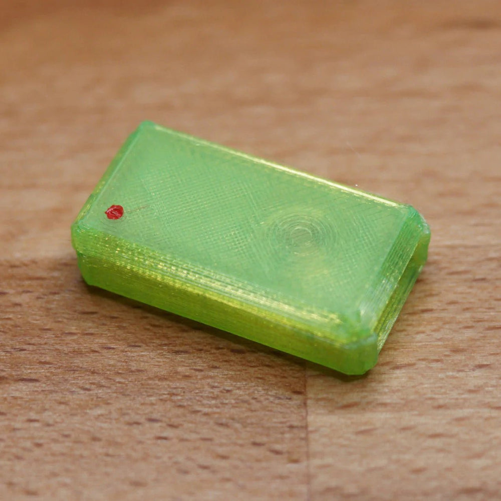 A single assembled green USB Nova case with a red LED, on a wooden surface