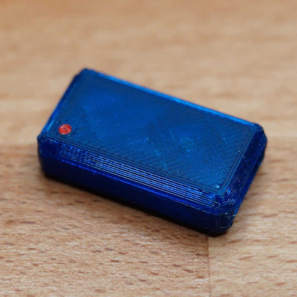 A single assembled blue USB Nova case with a red LED, on a wooden surface