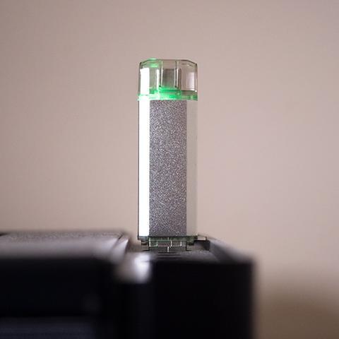 Srebrne urządzenie WiFi Deauther wpięte w port USB ze świecącą zieloną diodą sygnalizującą pracę