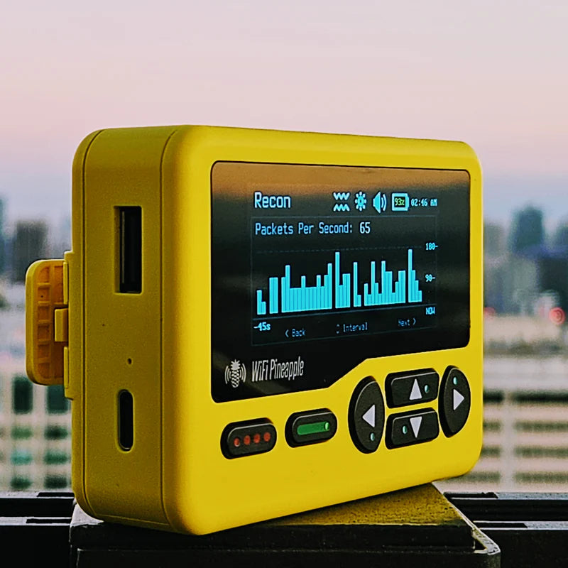 Žlutý WiFi Pineapple Pager s grafem průzkumu na obrazovce, v pozadí panorama města