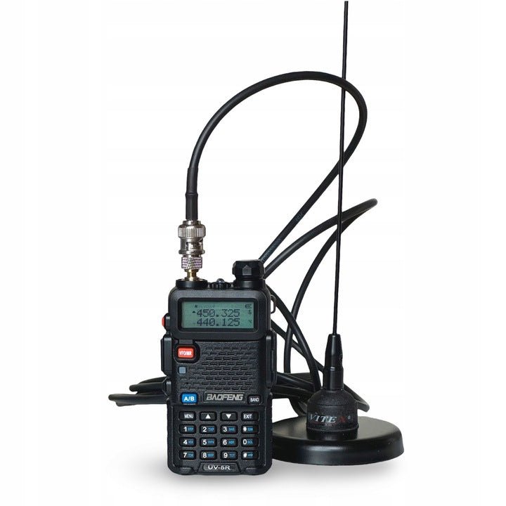 Vitex antenna on a magnetic base next to a Baofeng UV-5R radio connected through a BNC adapter