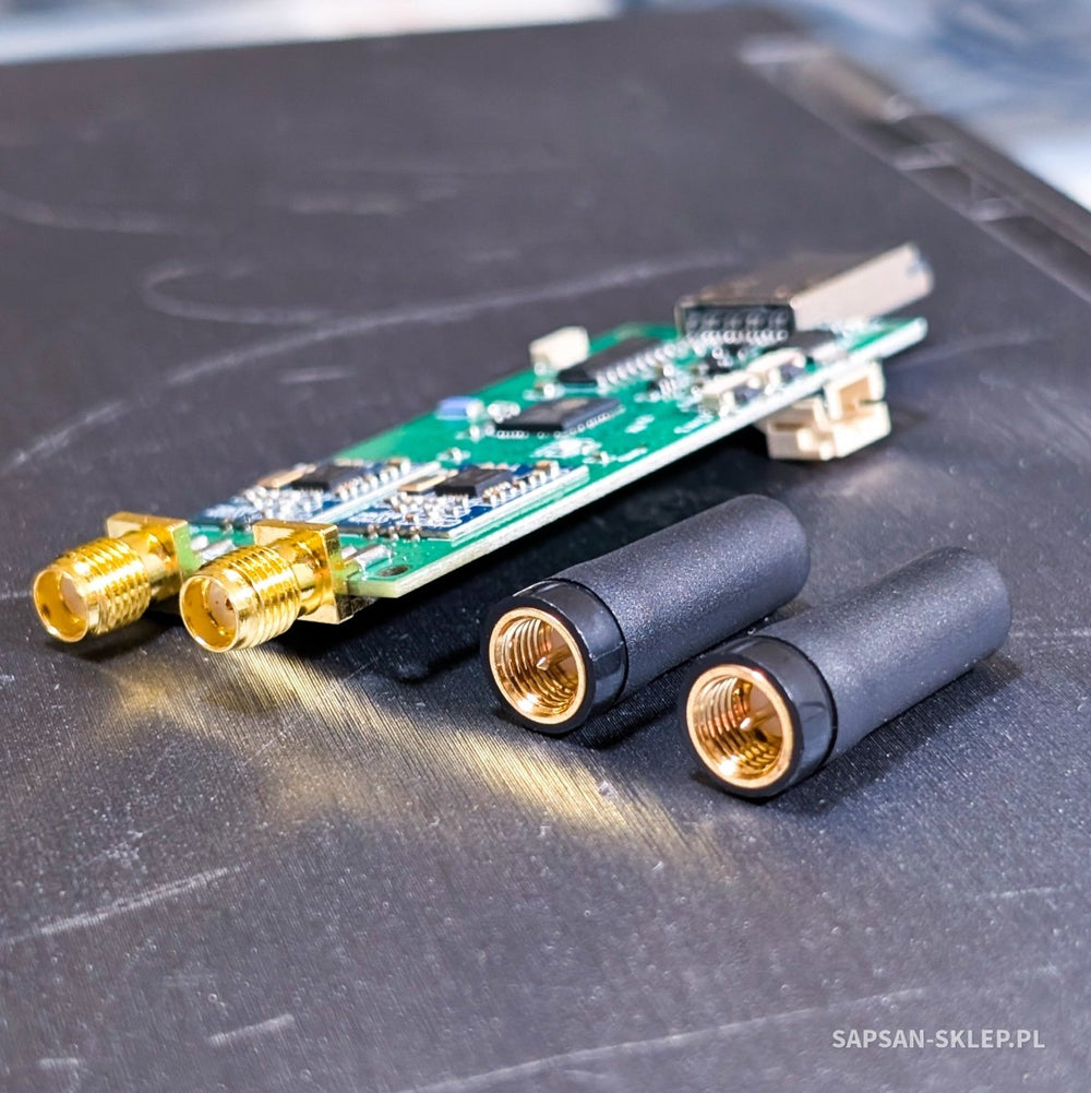 Evil Crow RF V2 board with two gold-plated SMA sockets lying next to two detached black antennas