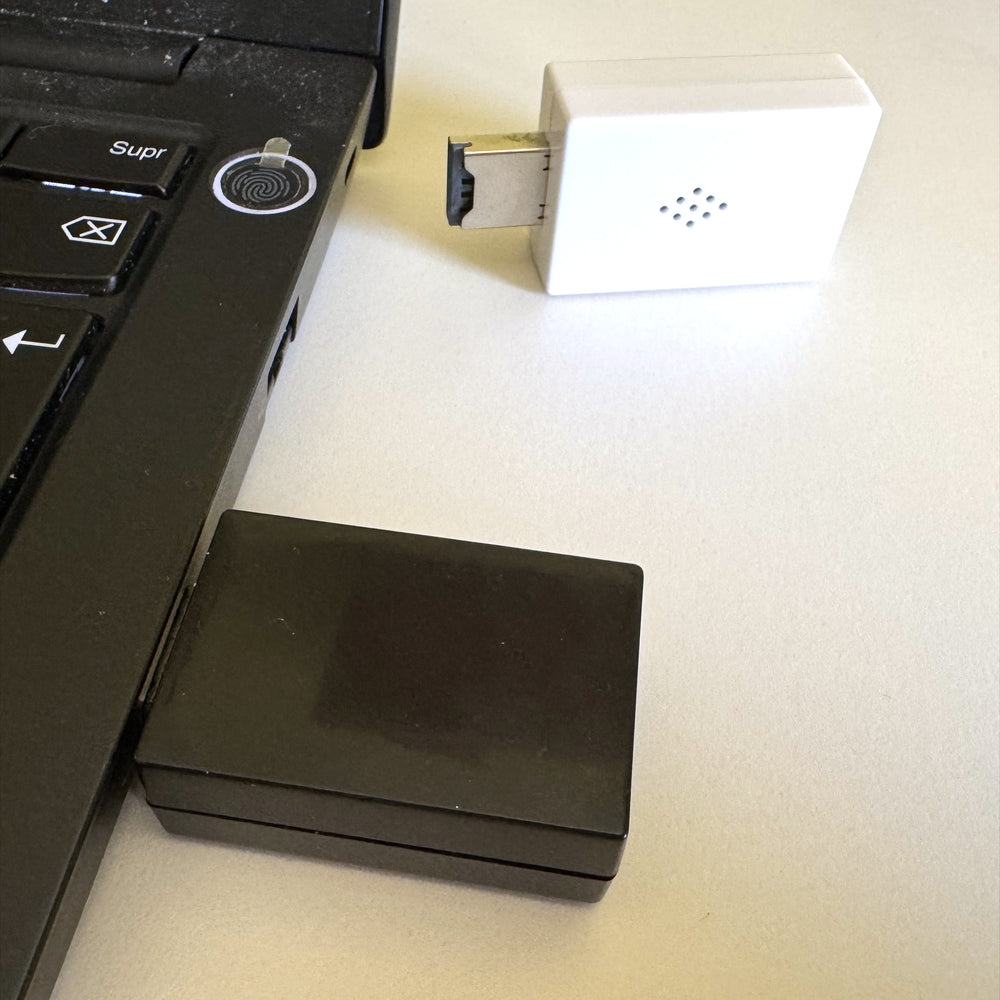 Evil Crow Keylogger V2 wpięty w port USB laptopa, obok drugi egzemplarz w białej obudowie