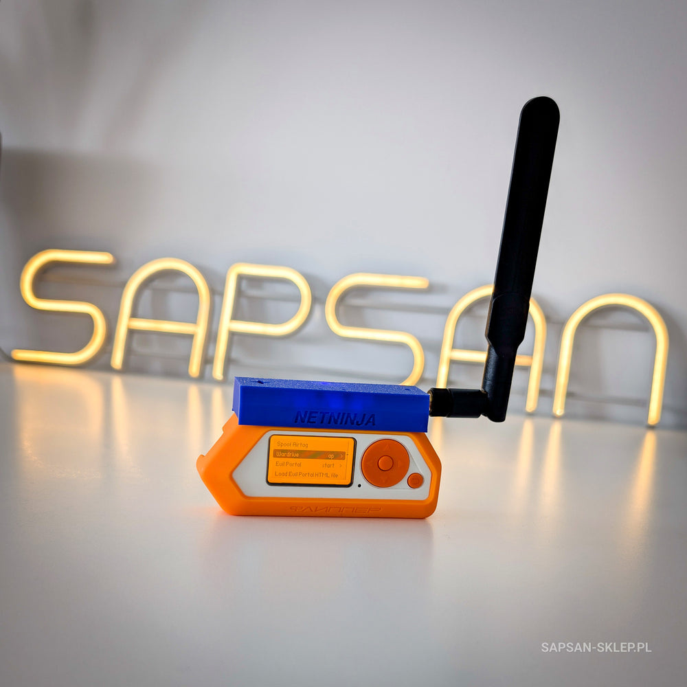 Flipper Zero in an orange case with the blue NetNinja module and a black antenna standing on a white desk in front of the glowing SAPSAN neon sign, Wardrive menu on the screen, SAPSAN-SKLEP.PL watermark