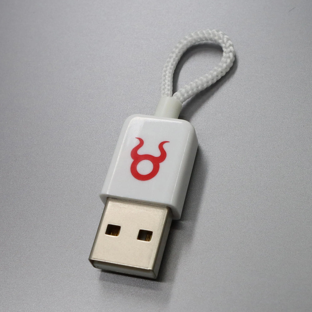 O.MG Plug od Hak5 v bílém provedení - bílé zařízení s konektorem USB-A, červeným logem býka O.MG a bílým pleteným poutkem, na šedém pozadí
