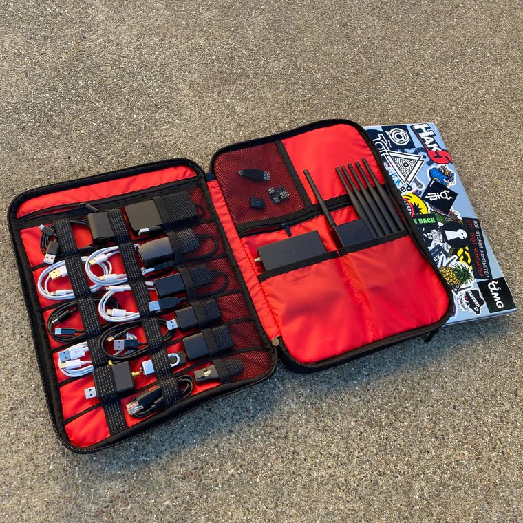 Otwarty organizer pokrowca Hak5 obok laptopa oklejonego naklejkami hakerskimi