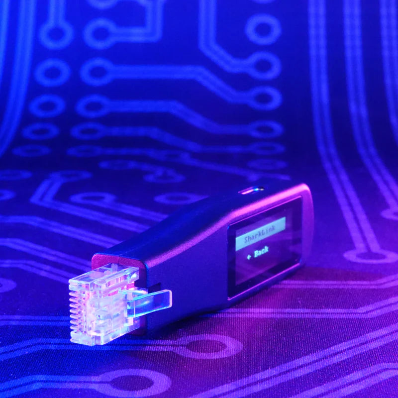 Dunkles Shark Jack Display schräg mit einem beleuchteten RJ45-Anschluss und einem Menü auf dem OLED-Display, vor einem UV-beleuchteten Platinenhintergrund