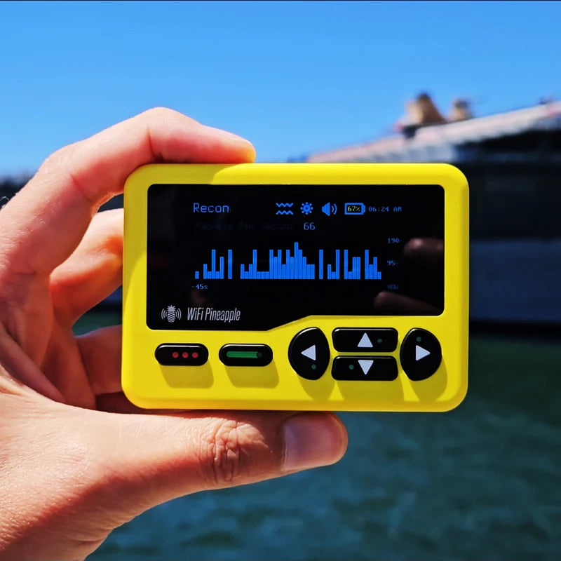 Žlutý WiFi Pineapple Pager držený v ruce s grafem průzkumu na obrazovce, v pozadí voda a loď