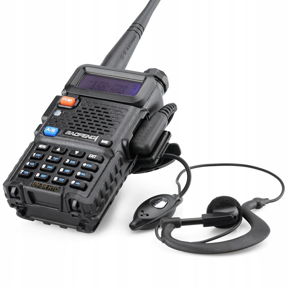 Schwarzes Baofeng UV-5R Funkgerät mit eingeschaltetem beleuchtetem Display, das Frequenzen anzeigt, und einem mitgelieferten Ohrhörer mit PTT-Taste