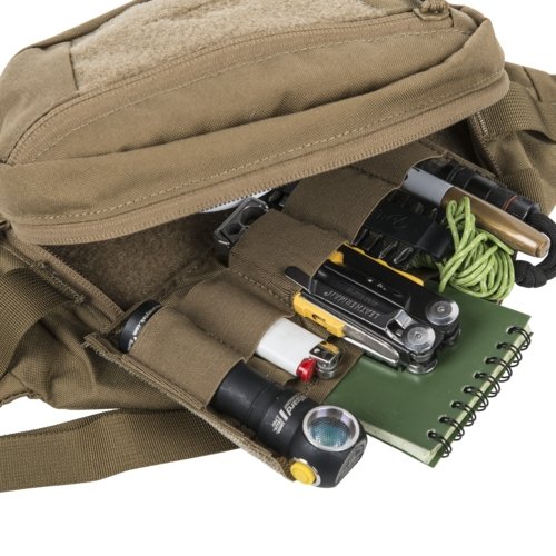 Helikon-Tex Bandicoot waist pack (coyote) open - the internal organizer panel with elastic loops filled with EDC gear: a flashlight, a lighter, a Leatherman multitool, a notebook, paracord and batteries, on white