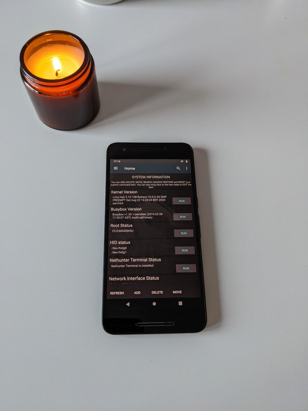 Czarny smartfon Nexus 6p z otwartą aplikacją Kali NetHunter na ekranie System Information (wersja kernela, Busybox, status roota i HID), obok świecy