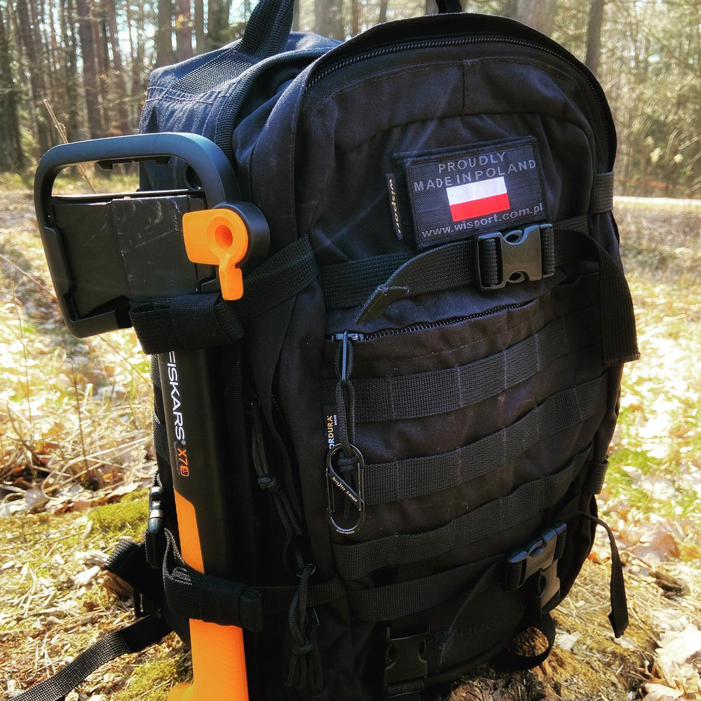 Czarny plecak Wisport Sparrow II w lesie z siekierą Fiskars przy boku, z naszywką Proudly Made in Poland, ujęcie lifestyle