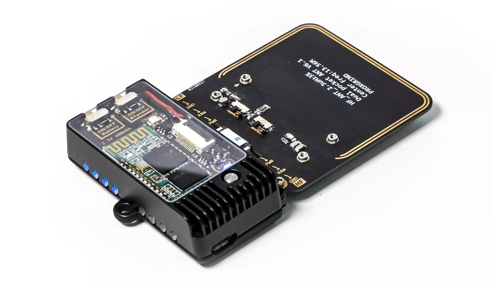Blueshark-Modul mit leuchtenden blauen LEDs, verbunden mit einer schwarzen HF-Antennenplatine mit goldener Leiterbahn - Ansicht aus einem Winkel