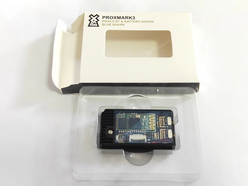 Blueshark-Modul in der Verpackung - eine weiße Schachtel mit Sichtfenster und der Aufschrift PROXMARK3 RDV4.0 BT & BATTERY ADDON BLUE SHARK, darunter das Modul im transparenten Blister