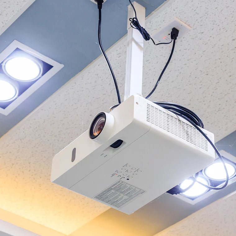 Biały projektor podwieszony pod sufitem biura z poprowadzonymi kablami HDMI i zasilania, sufit podwieszany z oświetleniem