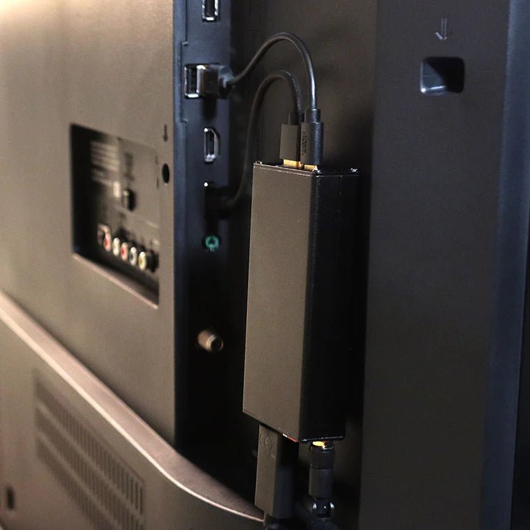 Hak5 Screen Crab wpięty w kabel HDMI z tyłu telewizora - mała czarna obudowa z anteną ukryta za ekranem