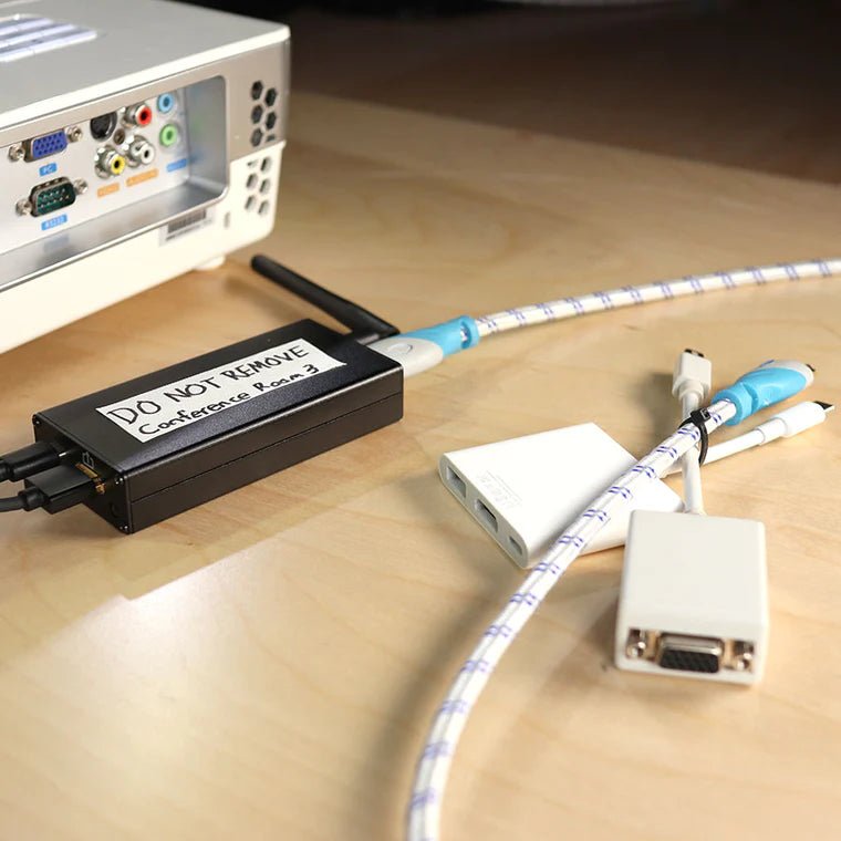 Hak5 Screen Crab w czarnej obudowie z naklejką DO NOT REMOVE Conference Room 3, wpięty między kable HDMI - zamaskowany jako sprzęt sali konferencyjnej
