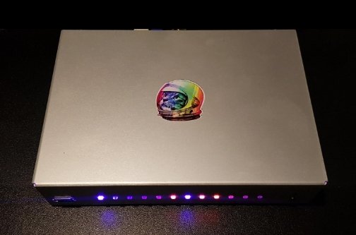 Router Turris Omnia 2020 w ciemnym otoczeniu ze świecącymi kolorowymi diodami RGB na froncie i naklejką na obudowie