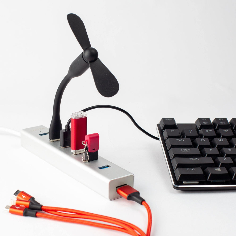 Unitek Y-3090 USB hub in use with a connected USB fan, flash drives and a cable, next to a mechanical keyboard