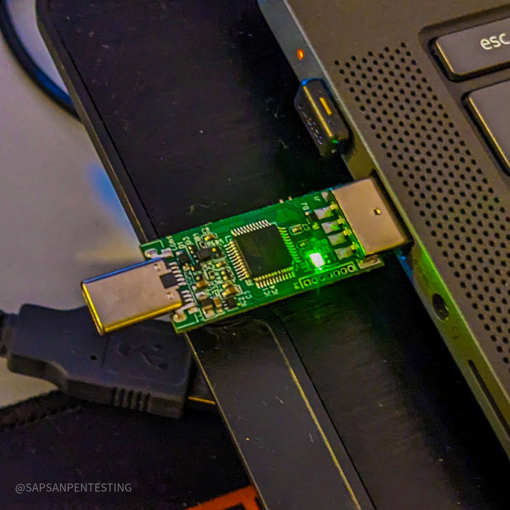 USB Rubber Ducky V2 от Hak5 - открытая плата, вставленная в USB-порт ноутбука, со светящимся зелёным светодиодом, на фоне клавиатура