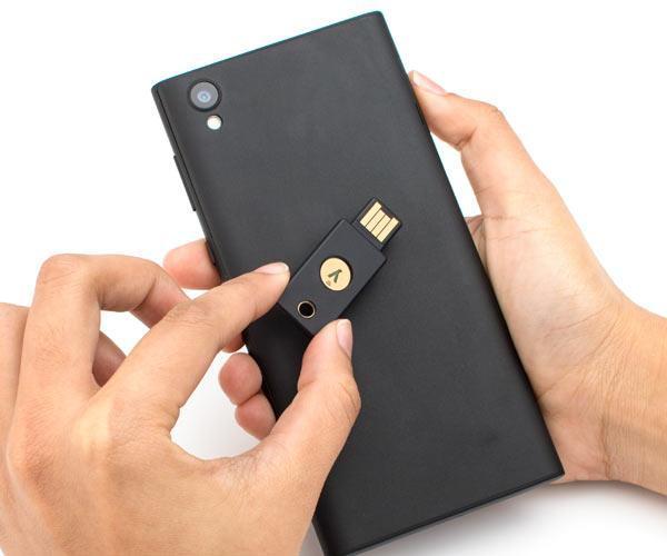 NFC use scene - a person tapping a black YubiKey 5 NFC to the back of a smartphone for contactless authentication